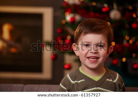 Closeup portrait of small boy at christmas, looking at camera, smiling.