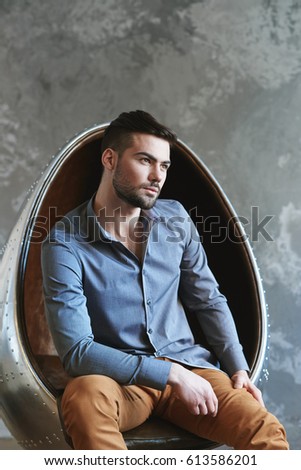 Man sitting in metal leather armchair grey background
