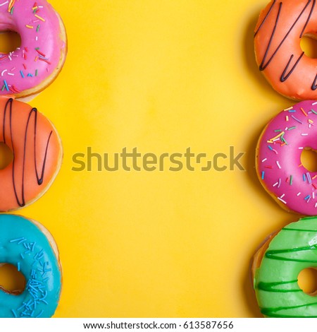 A set of sweet donuts on orange background. Top view with copy space.