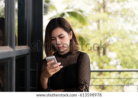 Portrait Asian young woman in black dress using mobile phone.