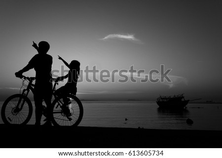 Silhouette lovely family at sunset over the ocean, biker family. Black and white.