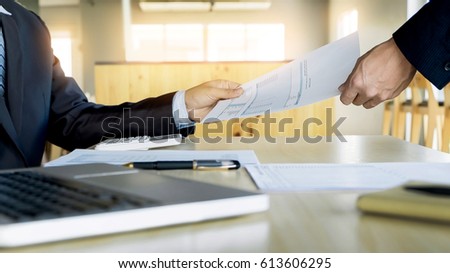 Businessman his colleague giving contract to read and sign.