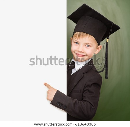 Boy in graduation hat pointing at blank placard.