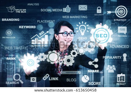 Young Asian businesswoman working with a digital screen while touching SEO button. SEO concept