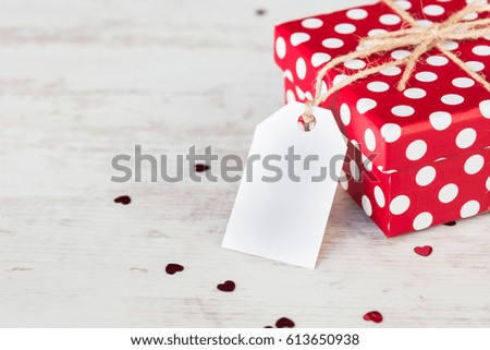 Close up of a red dotted gift box over white wood background. Copy space. Empty note.