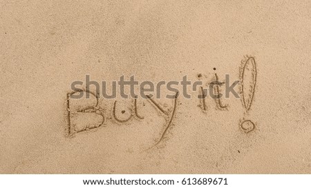 Handwriting words "Buy it!" on sand of beach