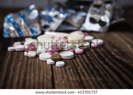 A pile of pills of different sizes on a wooden background