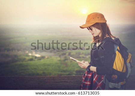 Female tourists are taking photos with their mobile phones over sunset background.