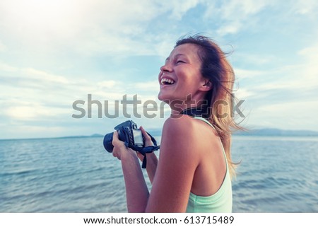 Young beautiful woman photographer with camera in hands on the seashore