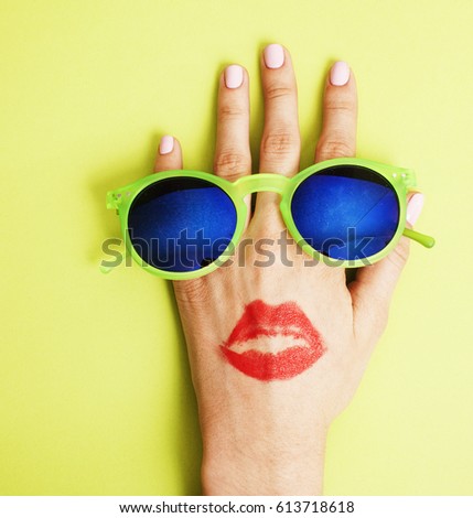 woman hand holding sunglasses on bright background, cosmetic summer vacation concept 