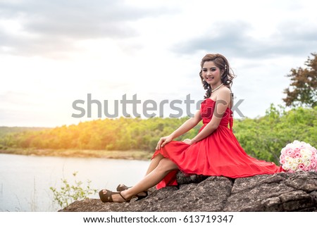 Beautiful young woman on the rocks in the forest Beside the reservoir.Thailand Concept.