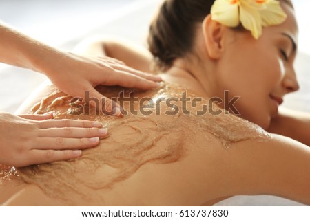 Young woman receiving scrub massage in spa salon Royalty-Free Stock Photo #613737830