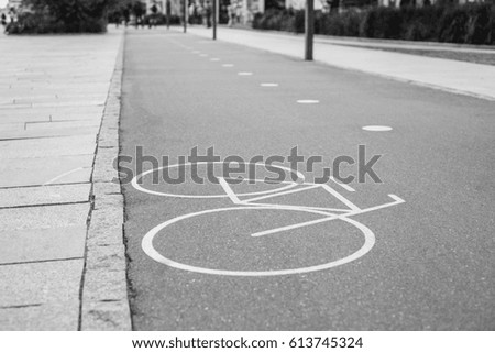 White painted bicycle way sign on asphalt in park.Separate cycling lane outdoor.Ride bike safe on bicycle road.Black & white photo