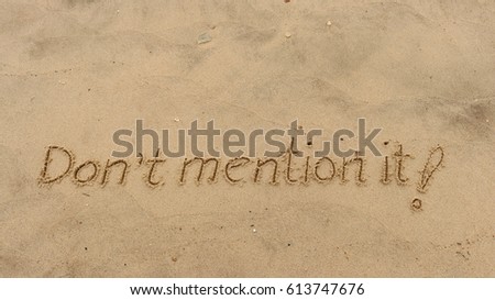 Handwriting words "Don't mention it!" on sand of beach