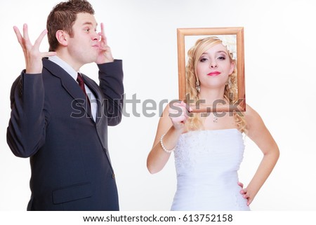 Wedding day, negative relationship concept. Groom and bride holding, posing with empty photo frame having bad argument.