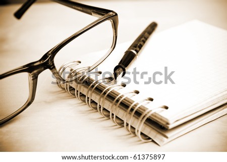 Fountain pen notebook and glasses in composition i sepia tone