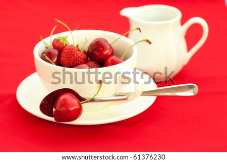 milk jug, cup, saucer and spoon  on a red background