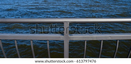 Metal fence on the background of blue sea water
