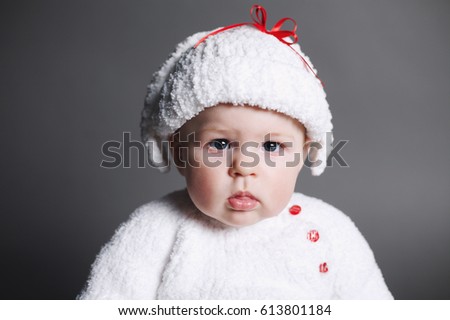 beautiful baby in a knit dress and cap on dark background