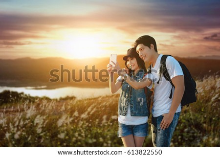 Traveling couple in love taking a selfie on phone at nature landscape