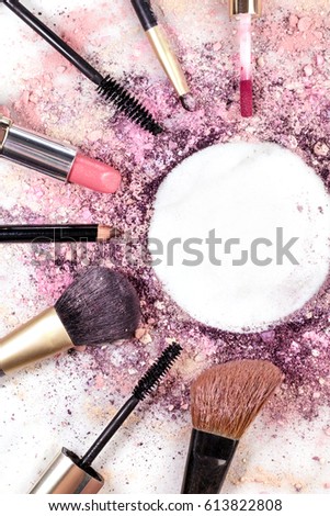 Makeup brushes, pencil, lipstick and other objects, forming a frame on a light background, with crushed powder and copy space. A vertical template for a makeup artist's business card or flyer design