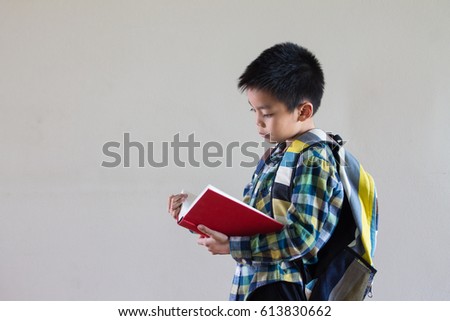 asian kid reading the book and shoulder bag