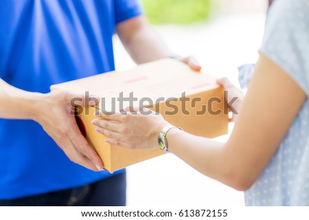 Asian woman receiving a package at home from a delivery guy Royalty-Free Stock Photo #613872155