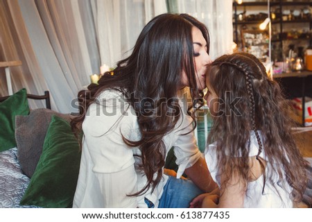 Mom kisses her daughter in bed.