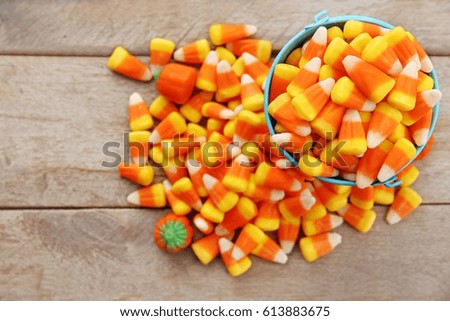 Bucket with tasty Halloween candies on wooden background