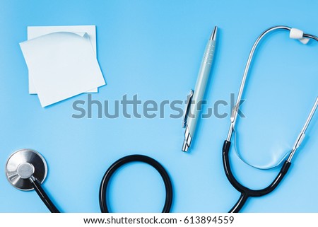 Stethoscope on a blue table, pen and sticker, concept of health and medicine