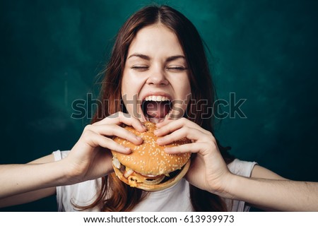 The woman opened her mouth to eat a hamburger, a hamburger in her hands, a woman with a hamburger