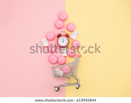 photo of marshmallows and alarm clock near shopping cart on the wonderful background in pop art style