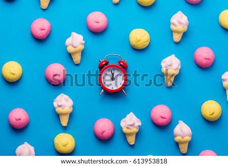 photo of tasty colorful marshmallows and alarm clock on the wonderful blue background