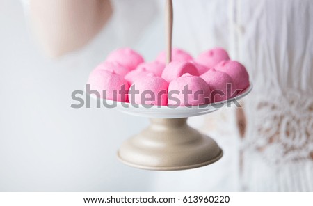 photo of young woman holding stand with pink marshmallows on the wonderful white background