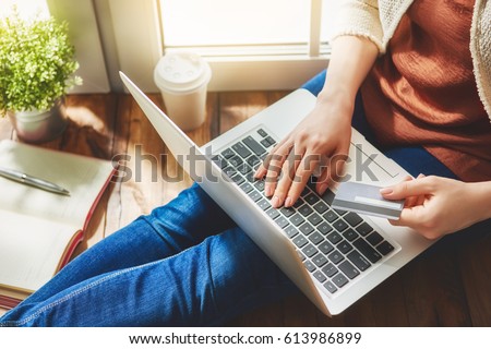 Woman is holding credit card and using laptop computer. Online shopping concept. Close up. Royalty-Free Stock Photo #613986899