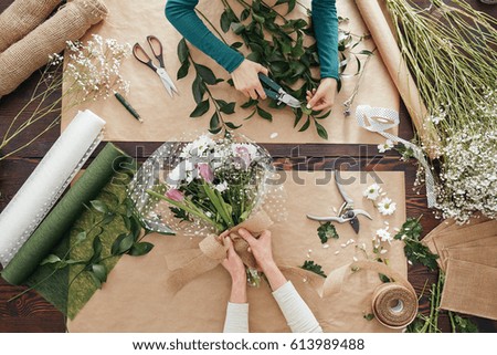 Florists making flower bouquets on a wooden table