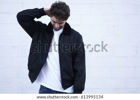 Young caucasian man dressed in casual clothing posing on street for fashion magazine collection. Handsome hipster guy wear brand jacket standing on white background with copy space area for advertise