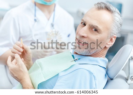 Mature patient looking at tooth sample while visiting dentist