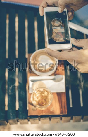 a business taking a photo of a coffee with his smart phone