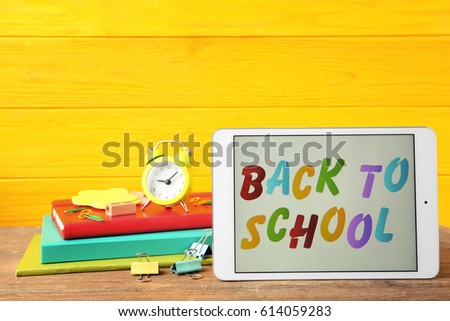Tablet with BACK TO SCHOOL message and stationery on wooden table