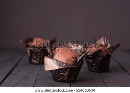 Group of chocolate cupcakes on a dark wooden table. Space for text
