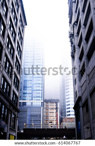 A landscape photograph skyline buildings covered in the misty fog. The view of the photo is from the ground and looking up at the downtown atmosphere,
