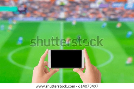 woman use mobile phone to take the photo of football match