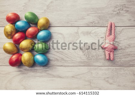 Colorful Easter holiday eggs are shiny and toy rabbit on a wooden table