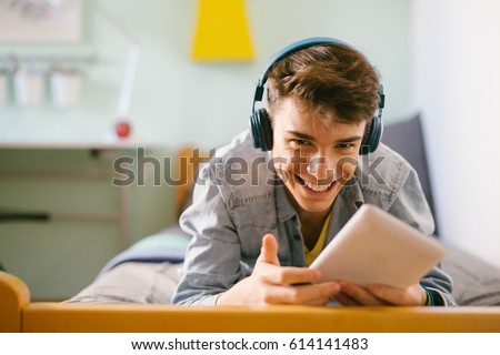 Teenage boy using tablet in his home. Royalty-Free Stock Photo #614141483