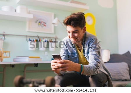 Teenage boy texting message in his room Royalty-Free Stock Photo #614145131