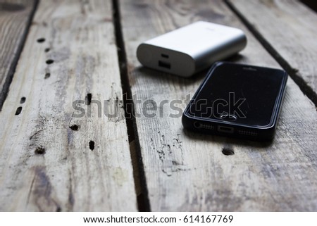Mobile phone and battery charging device close up background