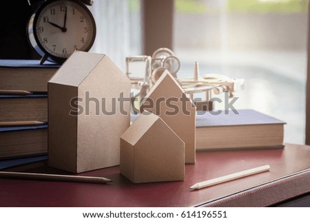house card board model with book and alarmclock with blur background