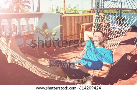 Young cheerful man lies  hammock patio sunshine Cuba rest.