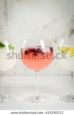 Selection of three kinds of gin tonic: with blackberries, with lime, with mint leaves. In glasses on a white background. Copy space close view 